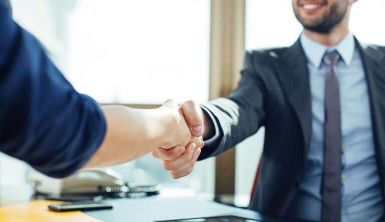 Two people shaking hands over a debt collection business deal.